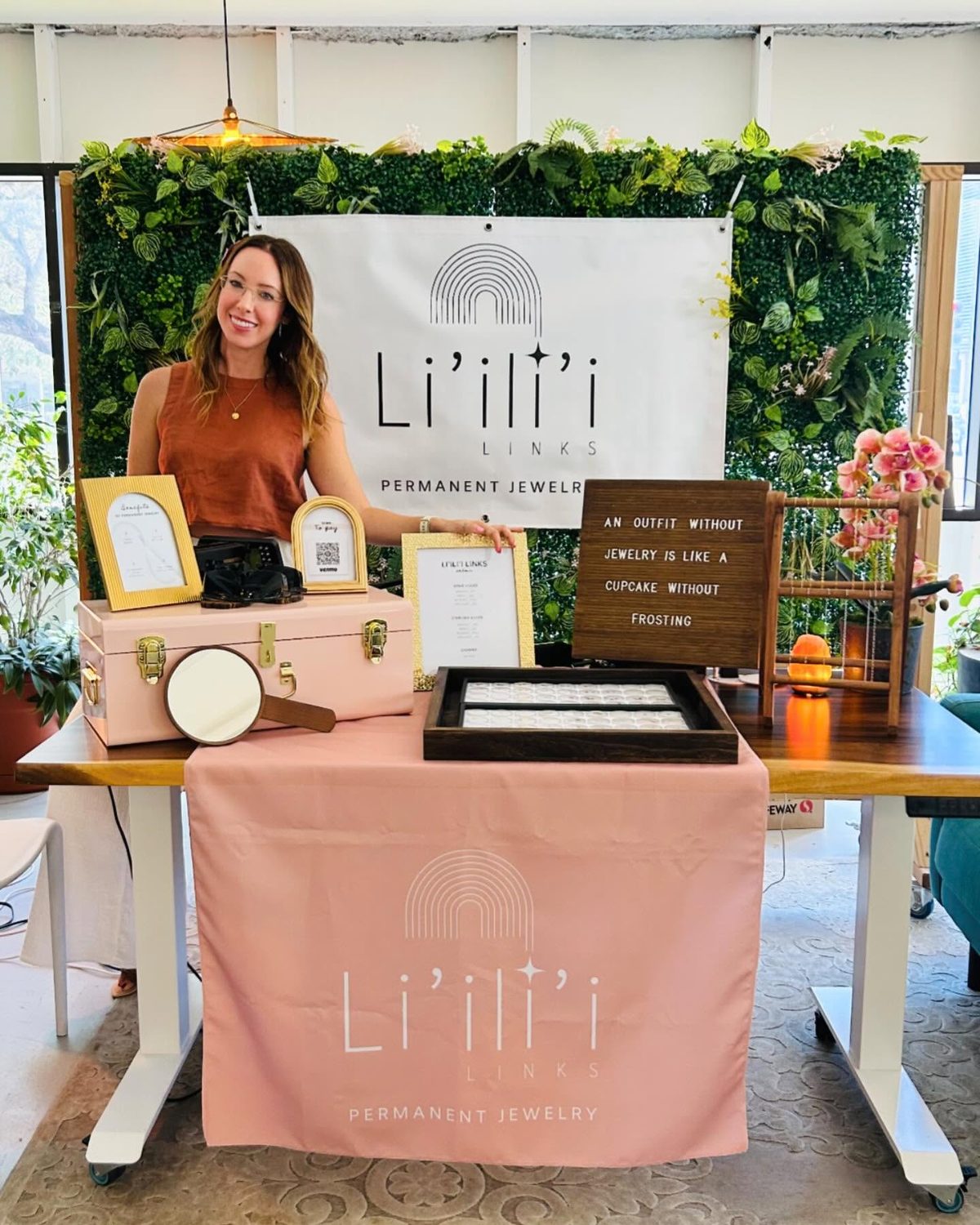 The Li'ili'i Links pop-up set up at an event with a greenery wall, banner and pink table